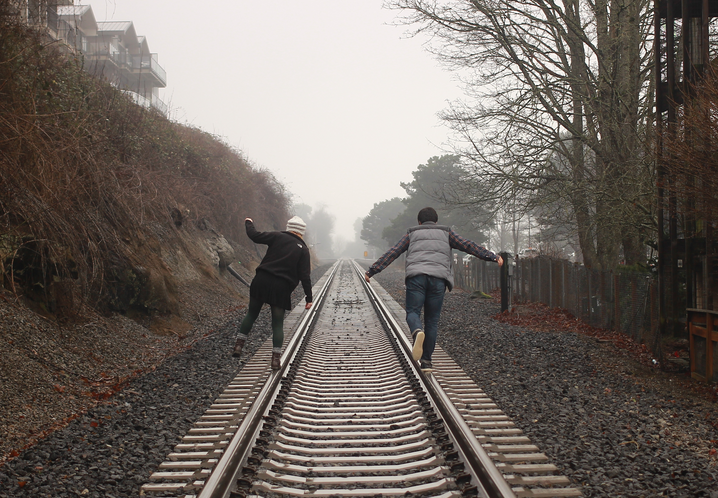 two people walking on railroad tracks