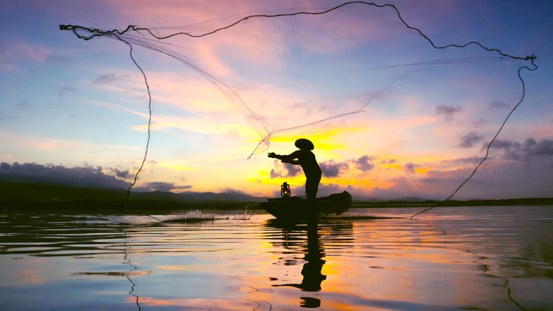 Fisherman throwing a net into the water