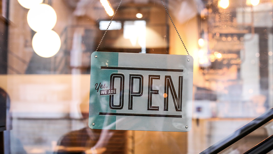 Sign hanging in window of storefront displaying, "Yes, We Are Open"