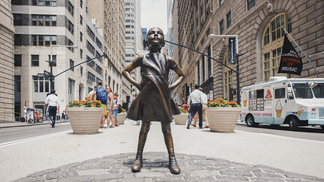 Photo of Wall Street sidewalk with bronze statue of a little girl in the center