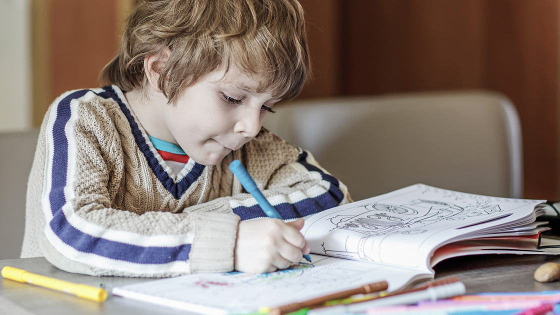 Young boy scribbling in coloring book