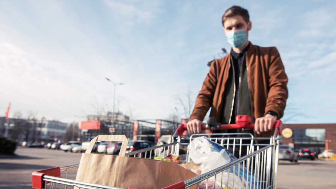 Man wearing N95 mask pushing grocery cart in parking log