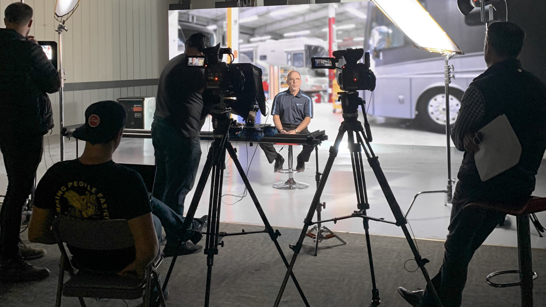Behind the scenes photo of video interview of Winnebago interview with RV assembly plant in background