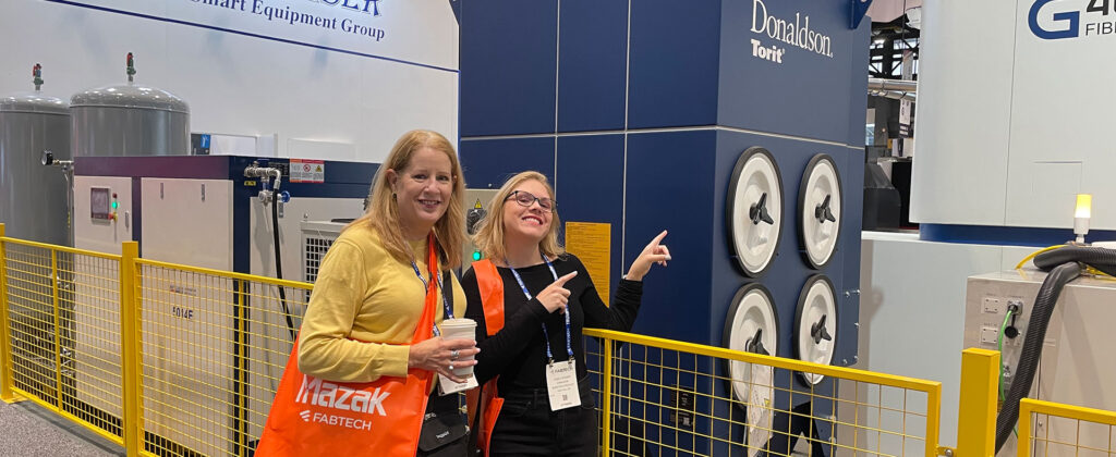 two women posing for the camera at FABTECH