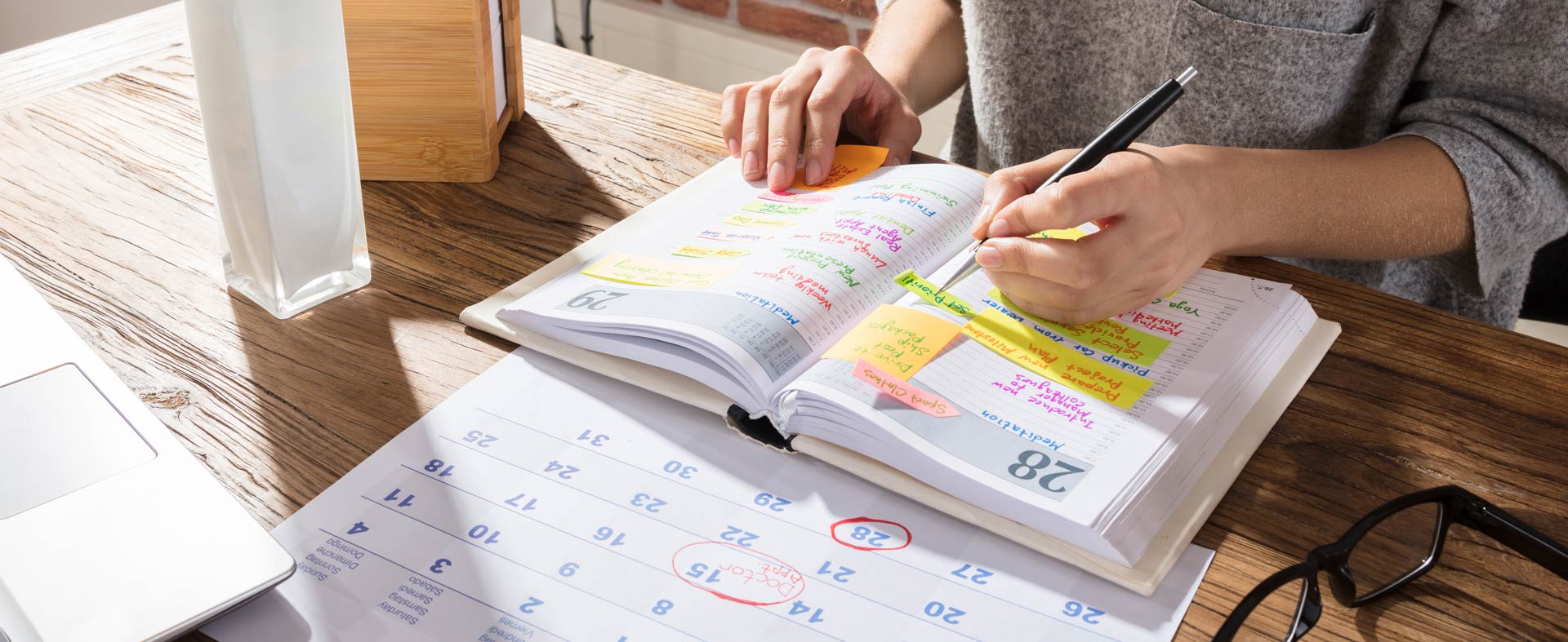 Person at a desk comparing their handwritten calendar to their digital calendar