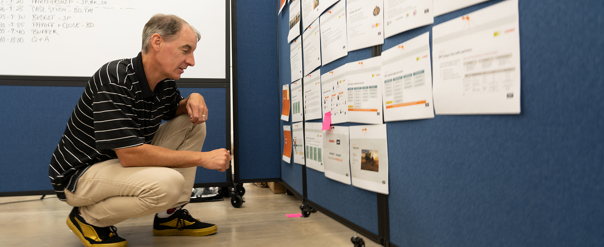 man crouching down looking at an artboard